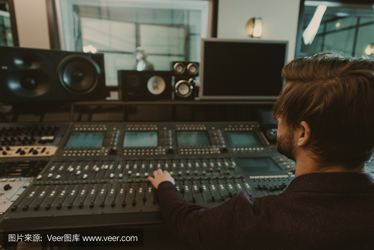 年轻英俊的声音制作人在录音棚工作