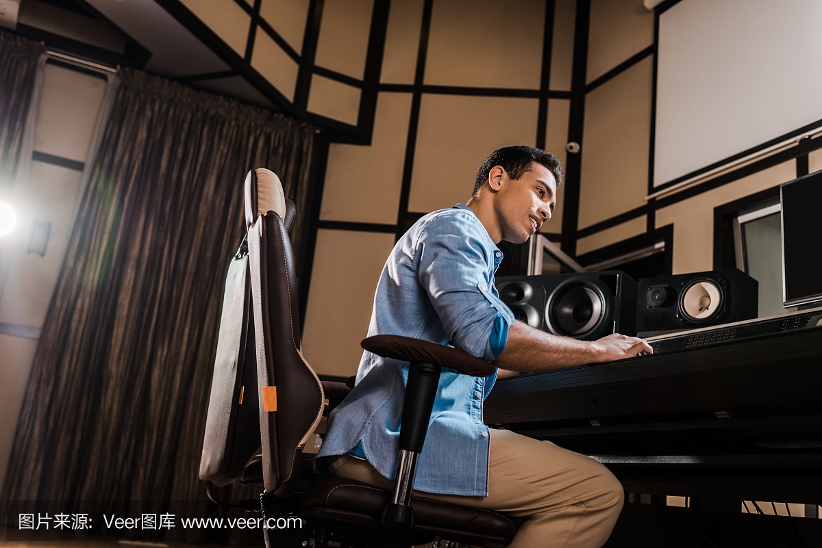 英俊的混合种族声音制作人在录音室混音控制台工作