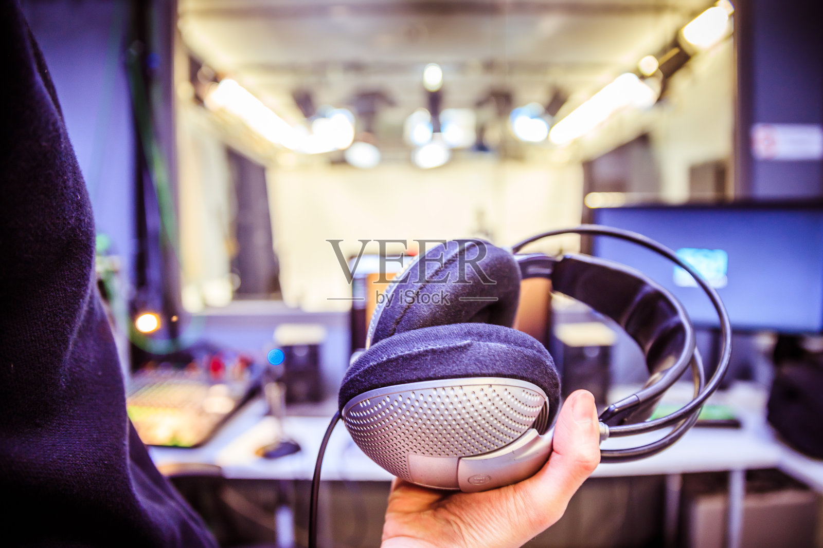 录音室录音:一个戴着耳机的年轻人正坐在录音室里,录音室的背景模糊不清